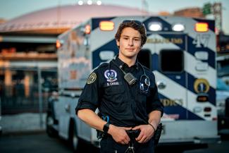 2022 graduate and paramedic Brendan Chace with ambulance and Superdome in background