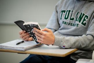 Person with a Tulane sweatshirt reviews their notes in Albrecht's class