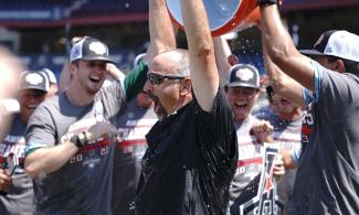 baseball players pour water over Tulane baseball Coach Jay Uhlman in celebration