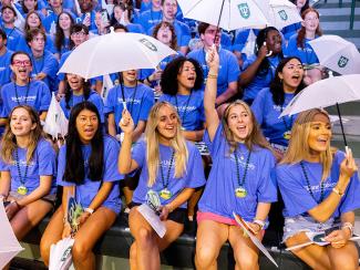 Students wave Tulane second-line umbrellas while seated during Convocation