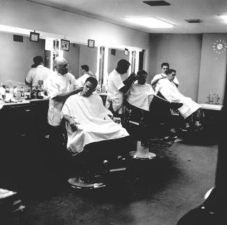 black and white photo of three barbers with customers in chairs in Tulane's barbershop in 1959