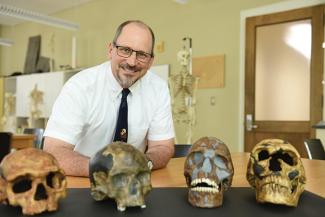 Trenton Holliday surrounded by four replica Cro-Magnon skulls