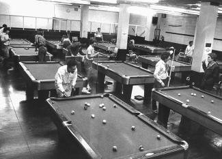 black and white image of students playing pool in room with pool tables in the 1970s