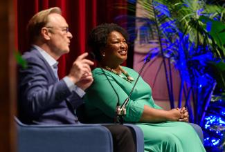 Stacey Abrams seated on stage in a green dress next to Lawrence O’Donnell 