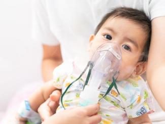 little baby is treated with vapor nebulizer placed over nose and mouth