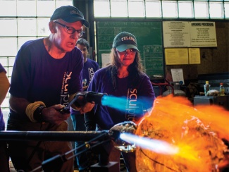 Gene Koss and a student shape glass with fire