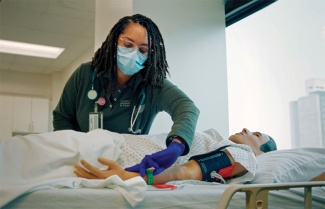 a medical worker trains on a manikin in a hospital bed