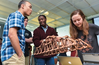 students participate in the Truss-Bust Competition and look at a small model of a structure