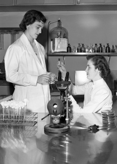 1953 photo of 2 nurses using a microscope in a lab