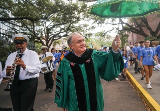 President Fitts holds a second line umbrella and parades with students and a brass band