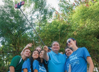 President Fitts uses a selfie-stick to take a photo with students 