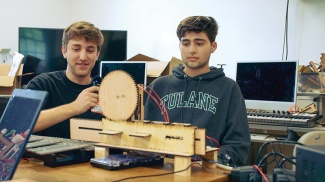 two students work to create a musical robot using wooden parts, computers, xylophone