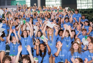 students dressed in blue t-shirts do the wave