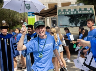 student holds second line umbrella with Cafe du Monde food truck in background