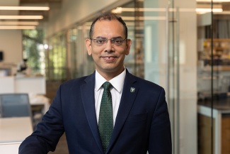 Hridesh Rajan portrait with offices and labs with glass walls in the background