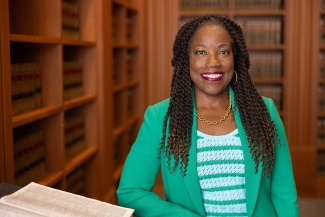 portrait of Marcilynn Burke standing next to a large book in a law library