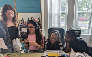 Camila Collazo Rivera mentors three middle school students as they record an announcement