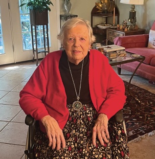 Sue Oppliger portrait sitting and wearing a red sweater