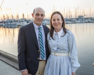 Robert and Libby Alexander stand by the water at sunset