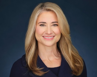 Portrait of Colette Hirstius. A woman with long, blonde hair smiles warmly against a dark blue background.