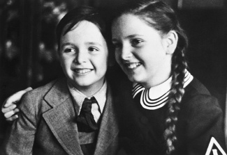 An old black and white photo of Steven Fenves and his sister, Estera Fenves as children. Estera has her arm around her brother.
