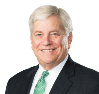 Smiling man with gray hair in a dark suit, white shirt, and green patterned tie against a plain white background. Professional and approachable tone.