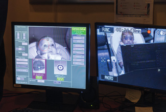 Monitors show babies with facial tracking graphics on grayscale displays.