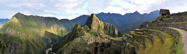 Panorama of Machu Picchu terraces, watcher's hut and Wuayna Picchu with shadow in early morning light.