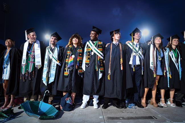 graduates in caps and gowns at the Commencement ceremony with night sky