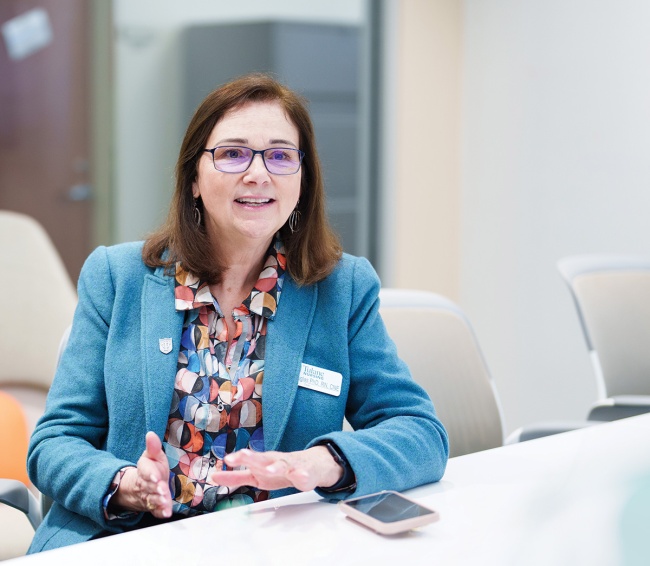 Brenda Douglas speaks while sitting at a conference table